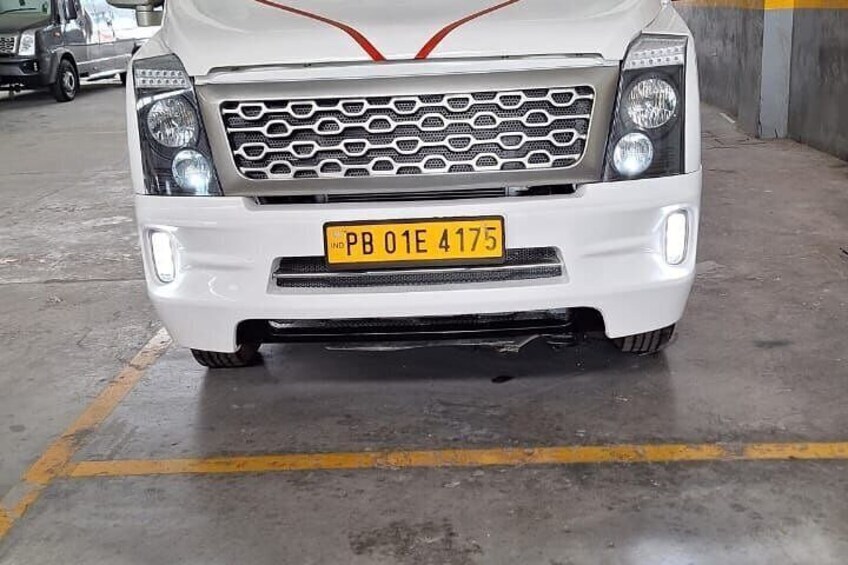 A white vehicle with a yellow license plate in a parking garage. 5
