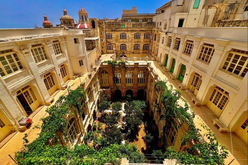 A courtyard surrounded by buildings with arched windows and a central fountain. 1