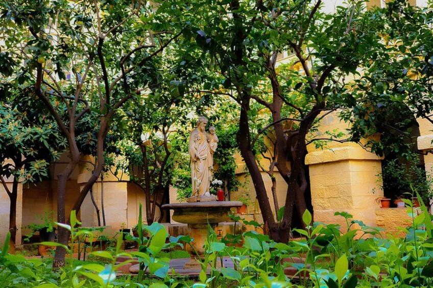 A garden with a statue, trees, and a fountain. 3
