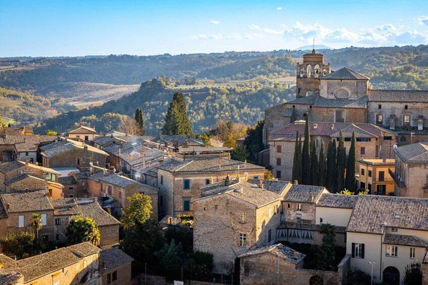 A historic town with stone buildings, a prominent church, and rolling hills in the background. 1