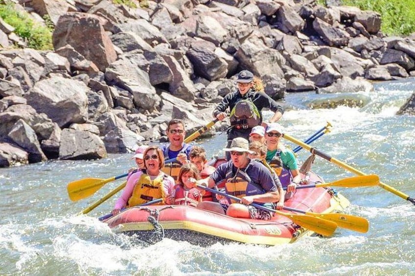 A group of people in a raft navigating a river with rapids. 4