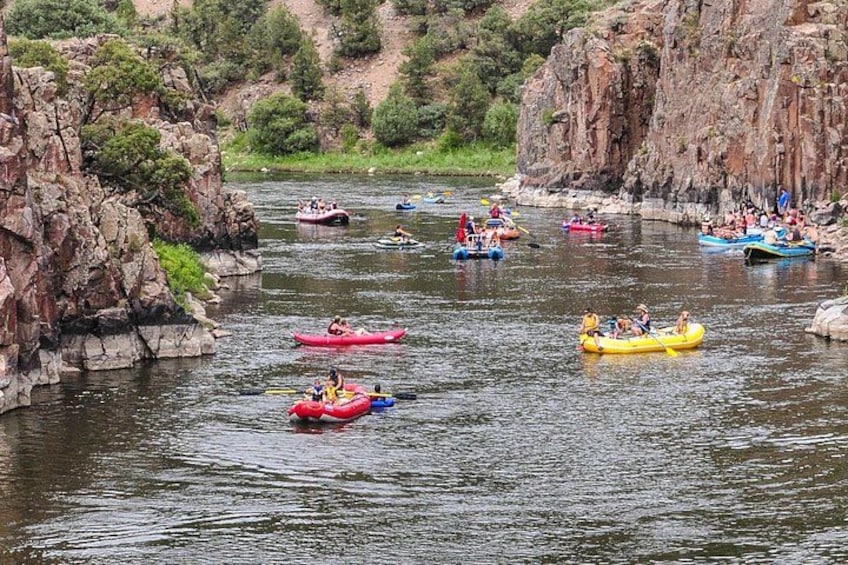 People rafting on a river surrounded by rocky cliffs. 3