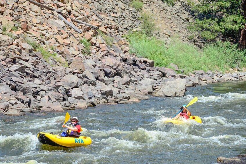 Two people kayaking on a river surrounded by rocky terrain. 2
