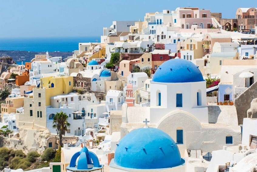 A coastal village with white and blue buildings, domed roofs, and a clear view of the sea. 1