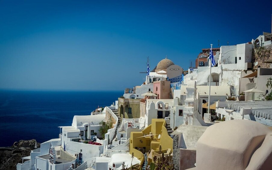 A coastal village with white buildings, a clear blue sky, and the sea in the background. 5