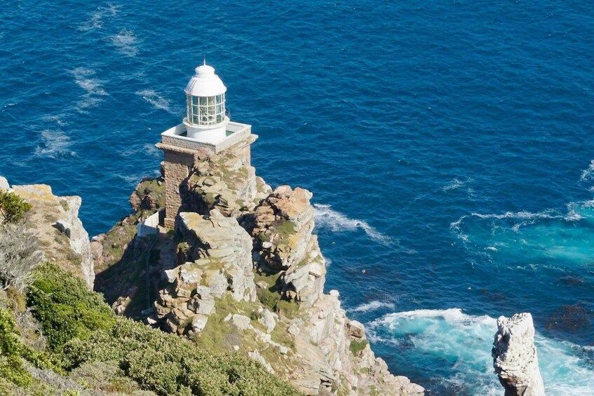 A white lighthouse on a rocky cliff by the sea. 4