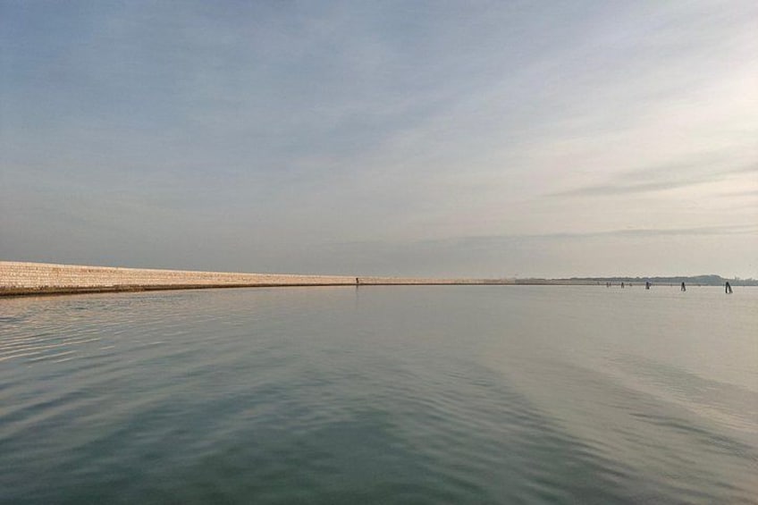 A calm body of water with a distant shoreline and a clear sky. 5