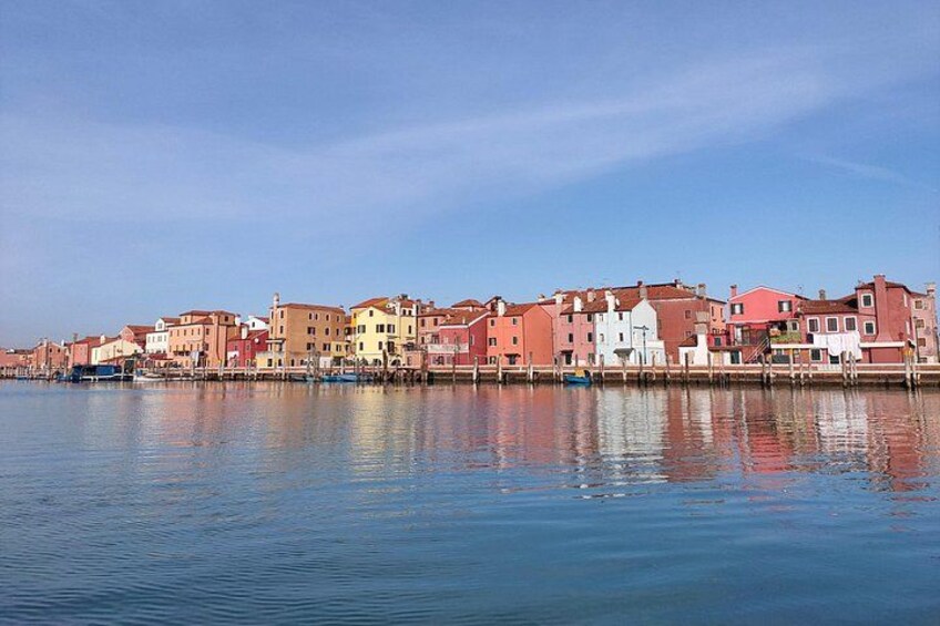 A waterfront with colorful buildings reflecting on calm water. 4