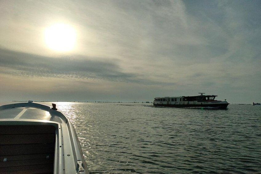 A boat on calm water with a clear sky and the sun low on the horizon. 2