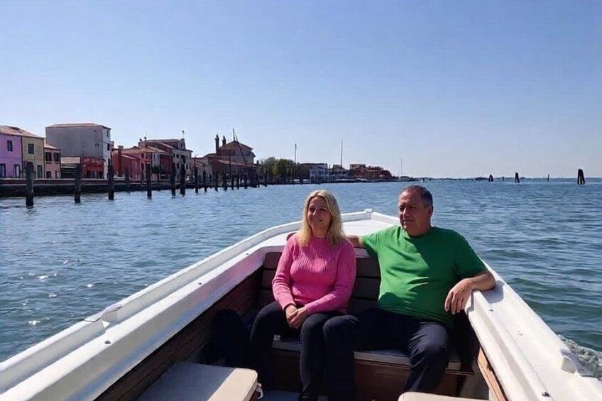 Two people on a boat in a canal with buildings in the background. 3