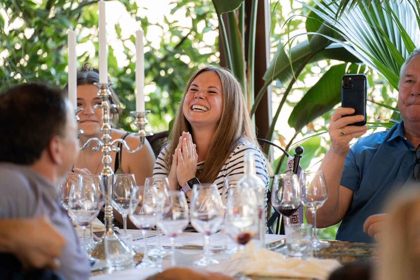 A group of people dining at an outdoor restaurant with wine glasses and candles on the table. 5