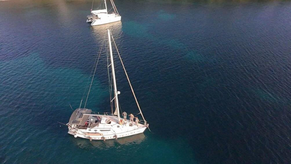 Un velero con mástil y velas en aguas turquesas tranquilas. 3
