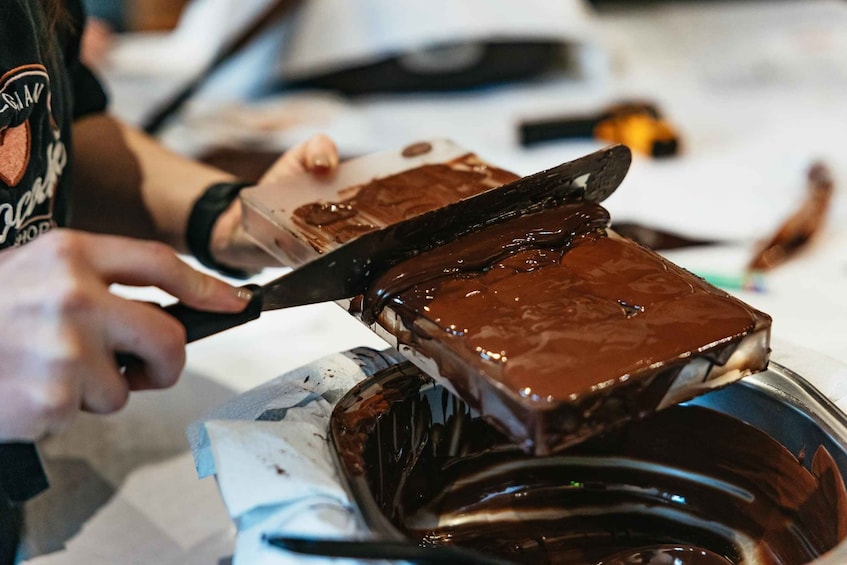 A person cutting a chocolate bar with a knife. 3