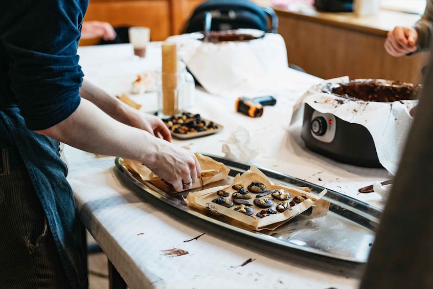 A person preparing food, placing items on a tray, with a baking tray and a pot in the background. 4