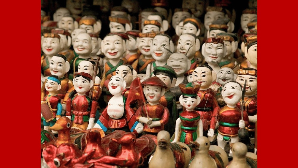 Una collezione di figure in legno tradizionali, alcune con cappelli e altre con armi, in vari colori. 1