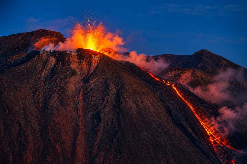 A volcanic eruption with lava flowing down the side of a mountain. 1