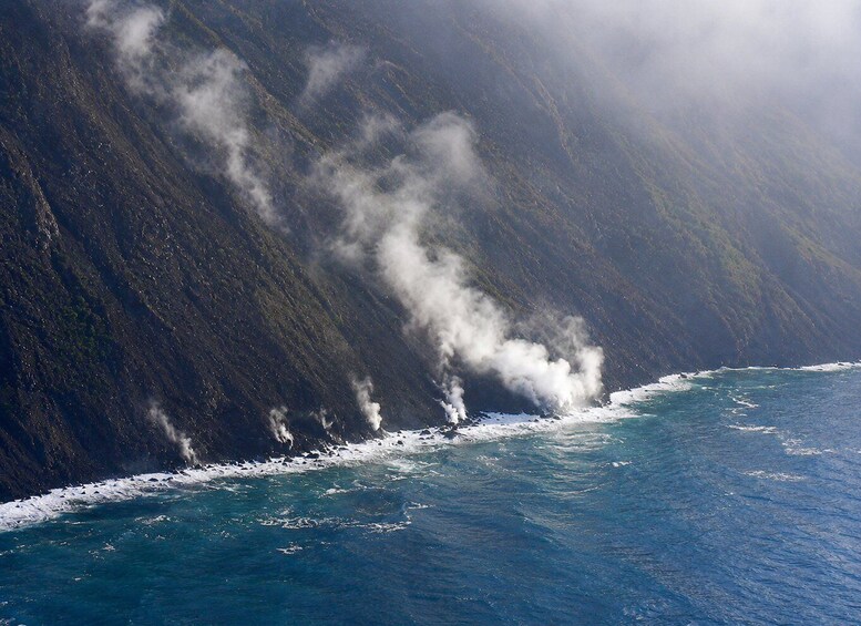 A coastal landscape with a steep cliff and ocean waves crashing against it. 4