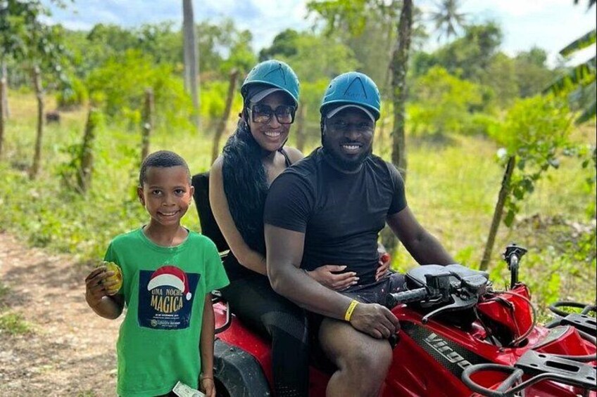 A person on a red motorcycle, another person sitting behind, and a child standing beside them. 2