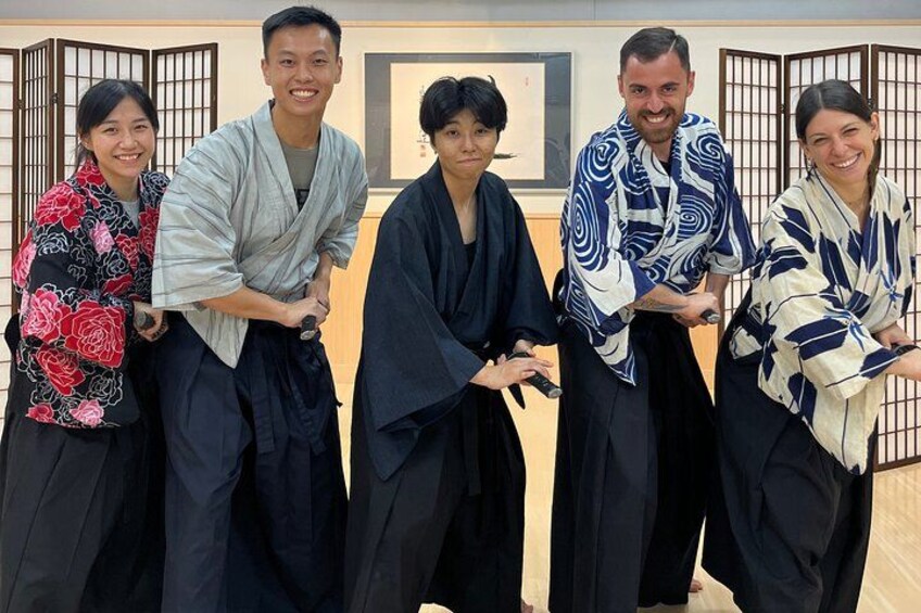 A group of people in traditional Japanese attire standing in a room with a wooden backdrop. 3