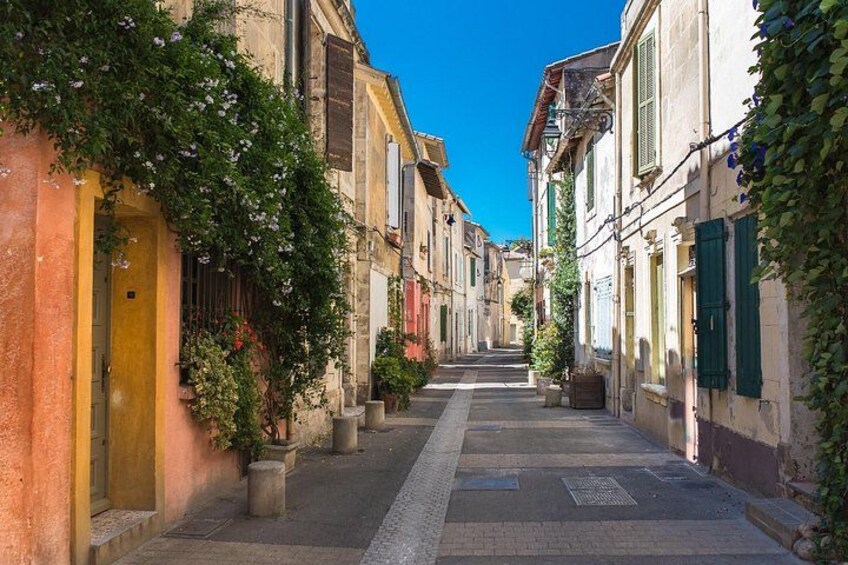 Eine enge Straße gesäumt von alten Gebäuden, einige mit grünen Fensterläden, und ein klarer, blauer Himmel. 3