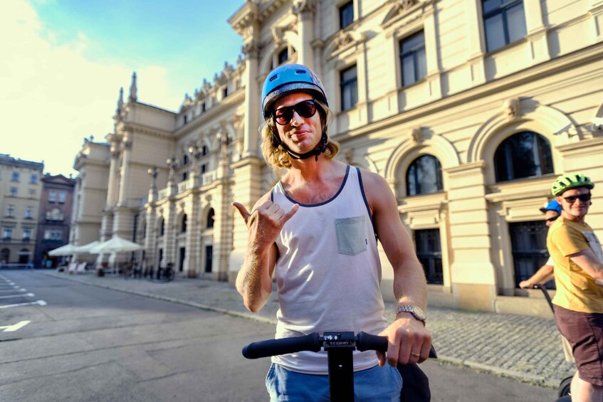 A person riding a scooter on a street with historic buildings in the background. 4