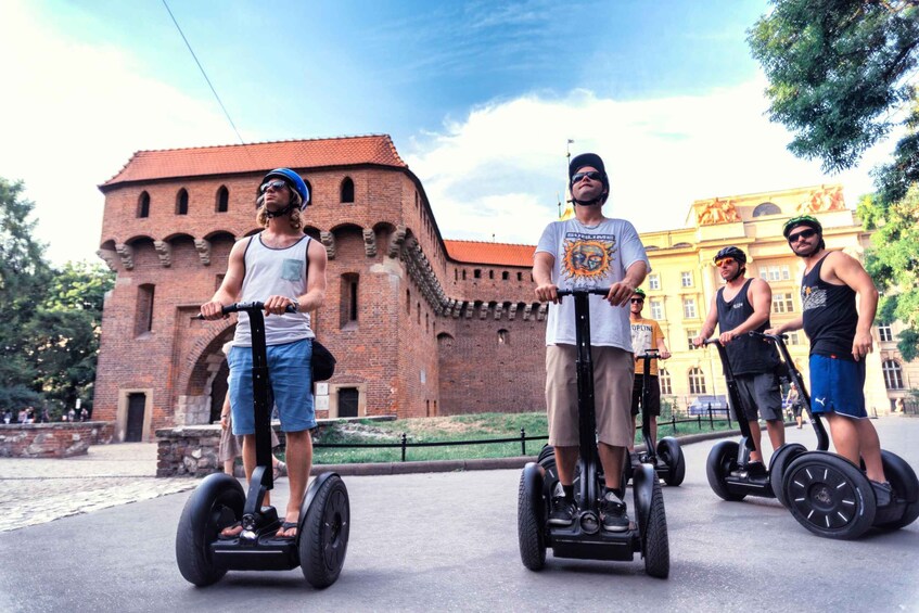 Four people riding Segways in front of a historic brick building. 1