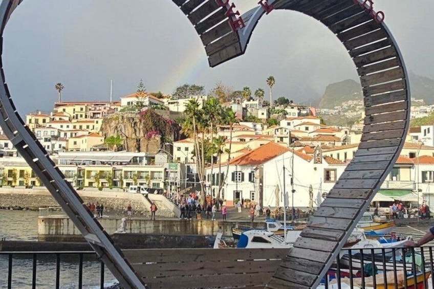A heart-shaped structure overlooking a coastal town with buildings and boats. 2