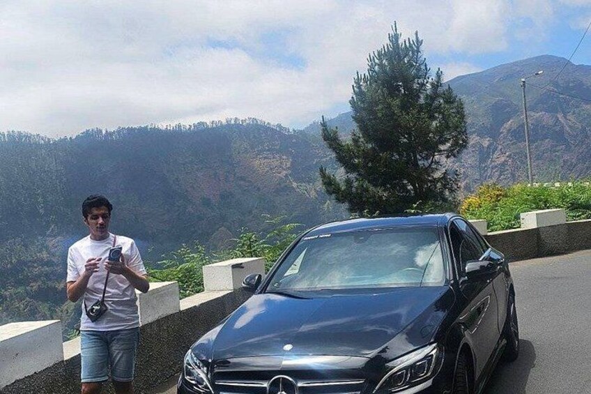 Un'auto nera parcheggiata su una strada con un paesaggio montuoso sullo sfondo. 4