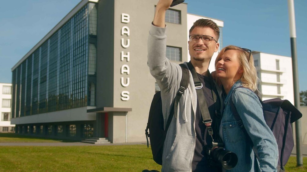 Two people taking a selfie in front of a building with 'BAUHAUS' written on it. 2