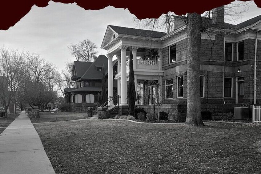 A large, historic building with columns and a symmetrical facade, surrounded by a well-maintained lawn and trees. 1