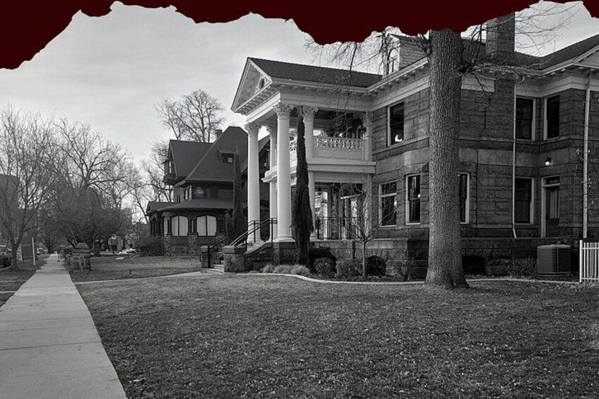 A large stone building with columns, a tree in front, and a sidewalk. 1