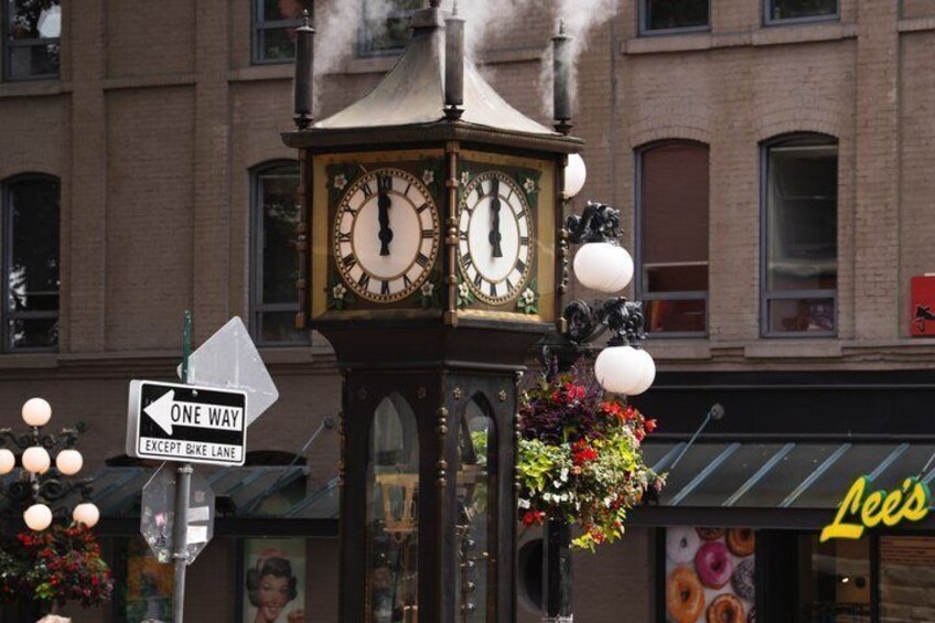 Una torre de reloj con una señal de vía única y una cesta de flores. 5