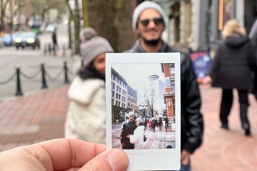 Una persona sostiene una fotografía de una animada escena urbana con edificios y peatones. 5