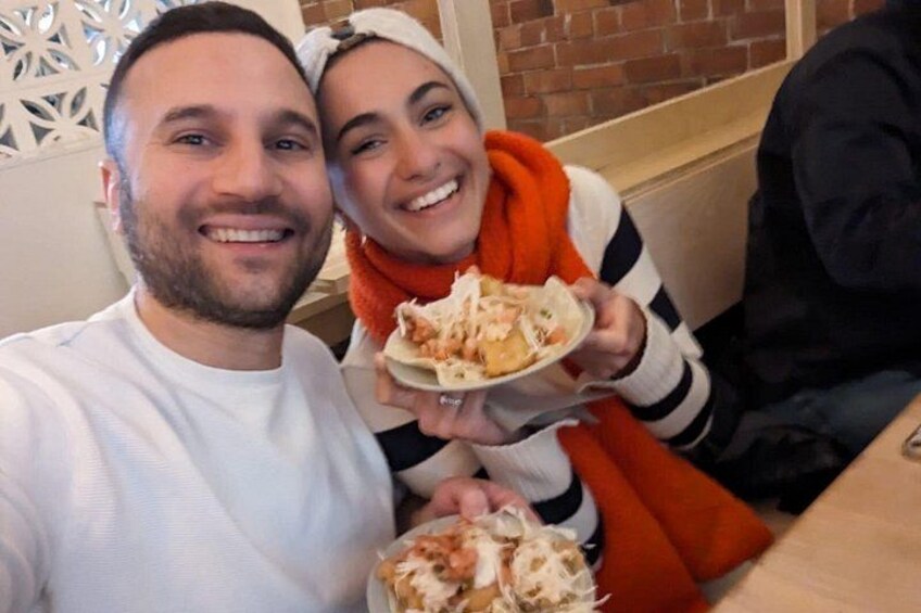 Two people sitting at a table with food. 3