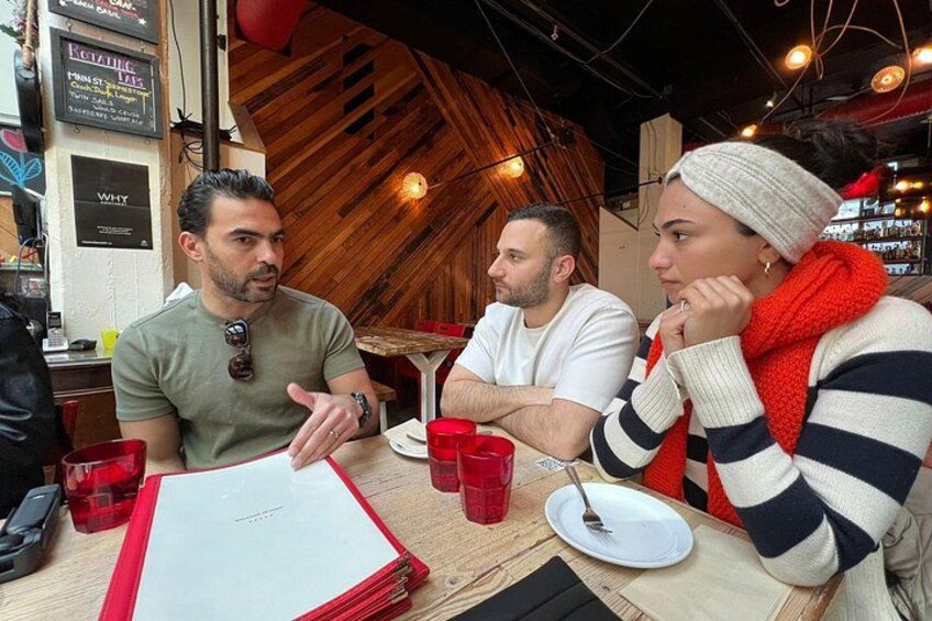 Three people sitting at a table with red cups and a menu. 2