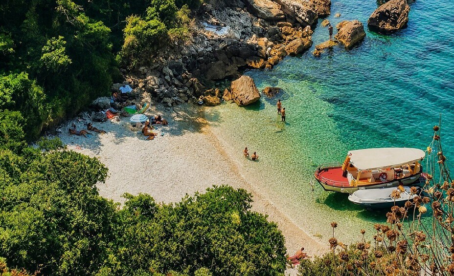 A beach with clear turquoise water, rocky outcrops, and a boat anchored nearby. 1