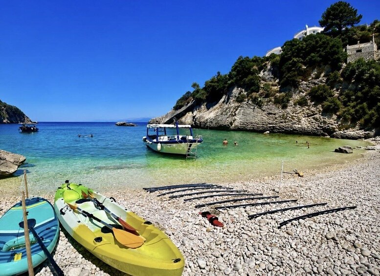 A pebble beach with kayaks, a boat, and rocky cliffs. 3