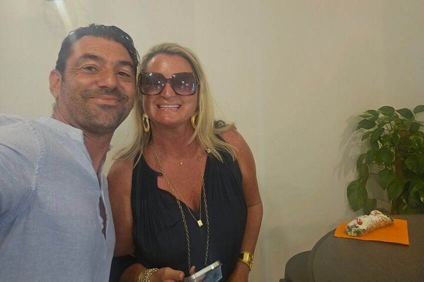 Twee personen poseren voor een foto, een bloempot en een stuk taart op een tafel. 5