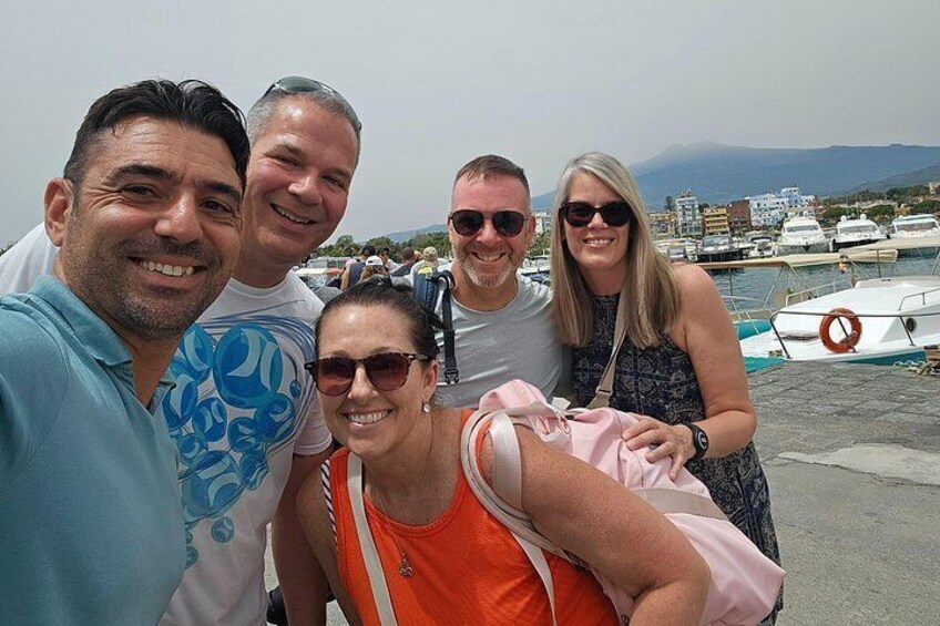Eine Gruppe von Personen posiert für ein Foto in einer Marina mit Booten und einer Bergkulisse. 2
