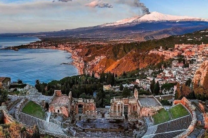 Un anfiteatro antiguo, un pueblo costero y una montaña nevada al fondo. 2