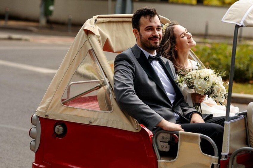 A couple in a vintage red and beige convertible car. 3