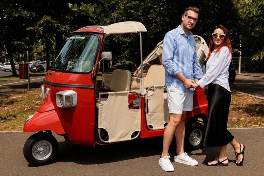 A red and beige golf cart parked on a paved area with trees in the background. 5