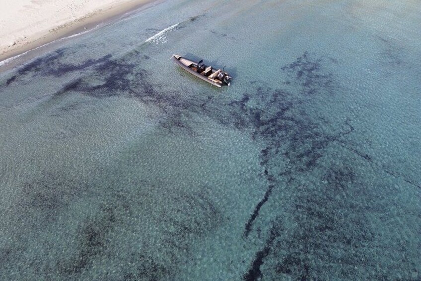 A boat on a clear blue sea with a sandy beach in the background. 2