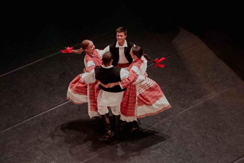 A group of people in traditional attire performing a dance on a stage. 4