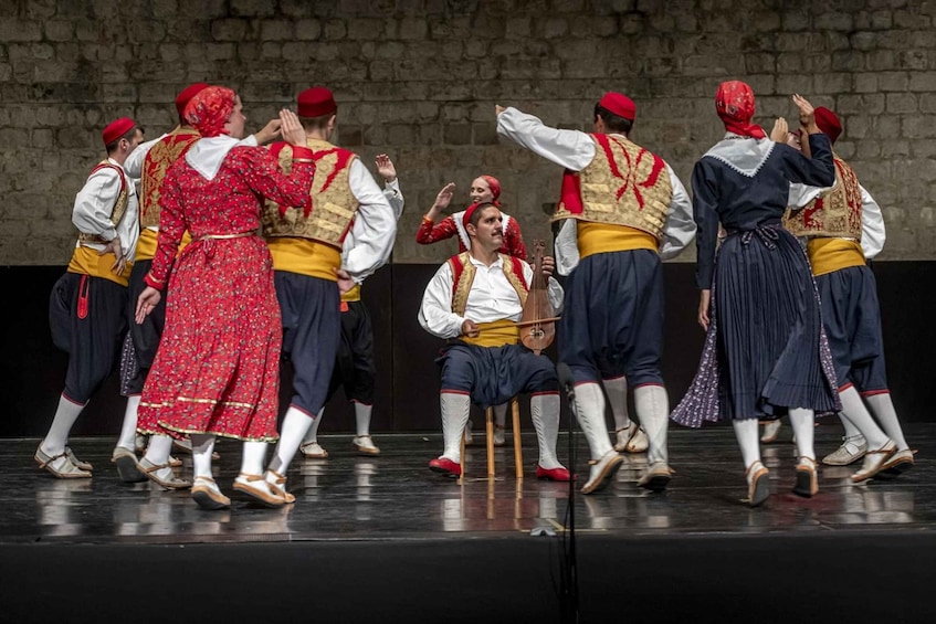 A group of people in traditional costumes performing on a stage. 1