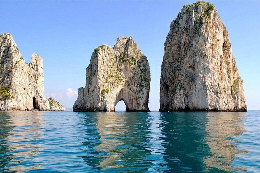 A coastal landscape with large rock formations and a clear blue sea. 2