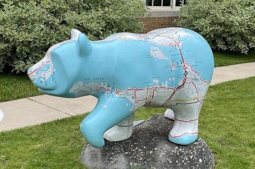 Una escultura de un oso azul con un mapa sobre su cuerpo, posado sobre una roca. 5