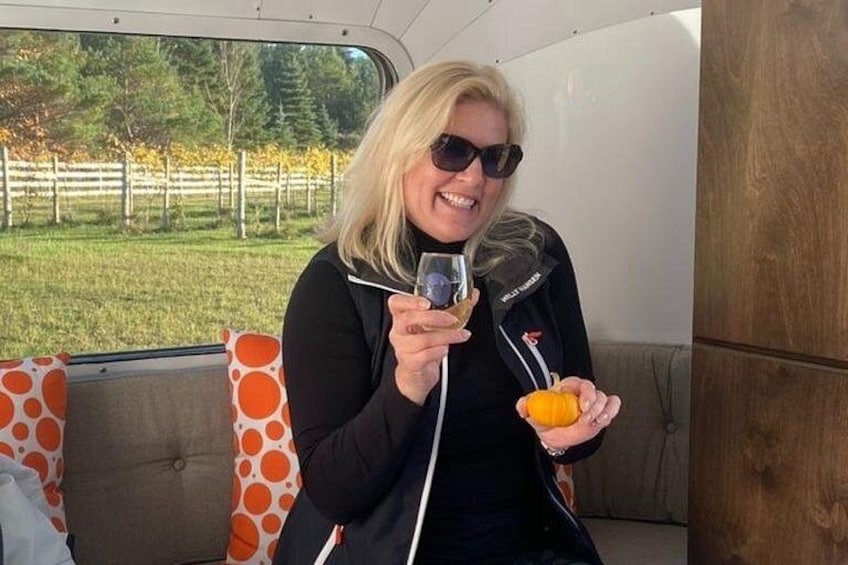 Una persona sosteniendo un vaso y un pequeño objeto naranja, sentada en un vehículo con cojines de estampado naranja y blanco. 3