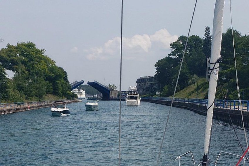 Un canal con barcos, un puente y abundante vegetación. 1