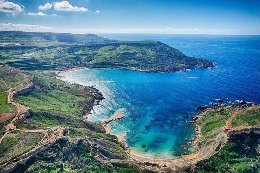 A coastal landscape with a clear blue sea, green hills, and a winding road. 5